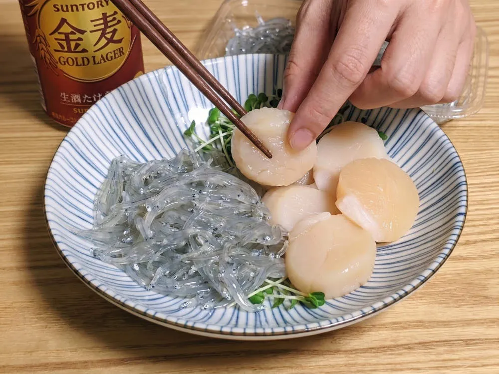 生しらすとホタテ貝柱を皿に盛り付ける