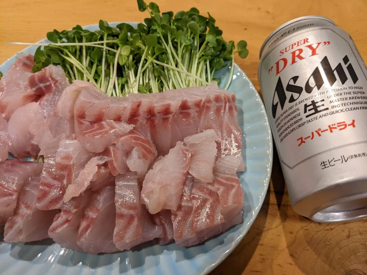 スズキの刺身にカイワレを添えたツマミとスーパードライ